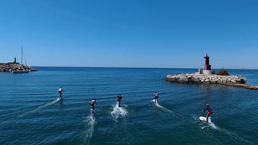 Aerial rear view of 5 persons riding Hydrofoiler Xe-1 water-bikes on the ocean in Spain