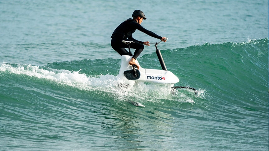 Man wearing a helmet riding a Hydrofoiler Xe-1 water-bikes on a wave in the ocean