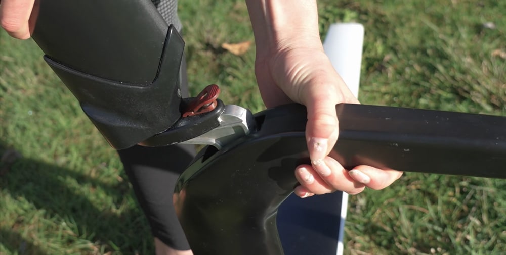 Close-up of a woman's hand connecting the front tiller throught the quick connect device on a Hydrofoiler SL3 water-bike