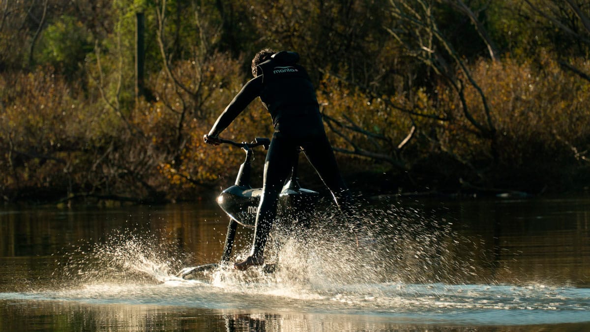 Back view of a man having fun riding the Hydroifoiler SL3 water bike on a river