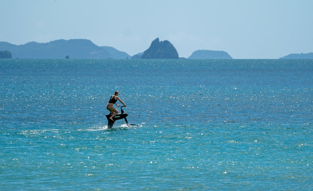 Girl riding the hydrofoil SL3 water bike in the ocean in New Zealand